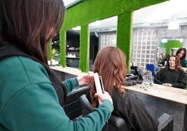 Irene Martín realiza ondas en el cabello a una clienta en su salón de belleza.