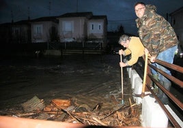 Vecinos de Miranda de Azán intentando retirar maleza en uno de los ojos del puente para evitar que el agua entrara a sus casas durante la riada de enero de 2023.