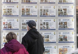 Una pareja mirando los anuncios de alquiler en una inmobiliaria.