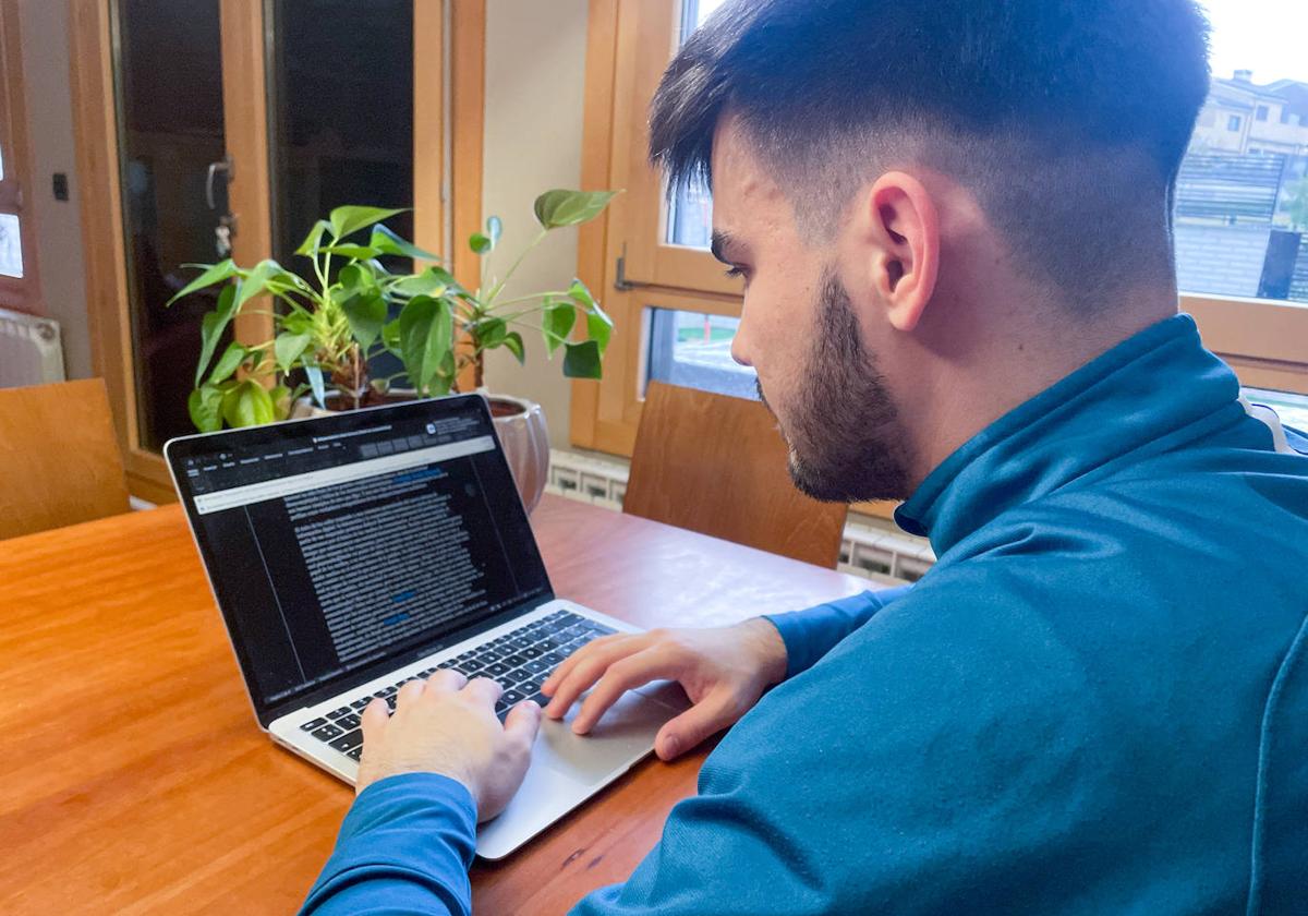 Un joven, con su ordenador, teletrabajando desde una estancia de su domicilio.