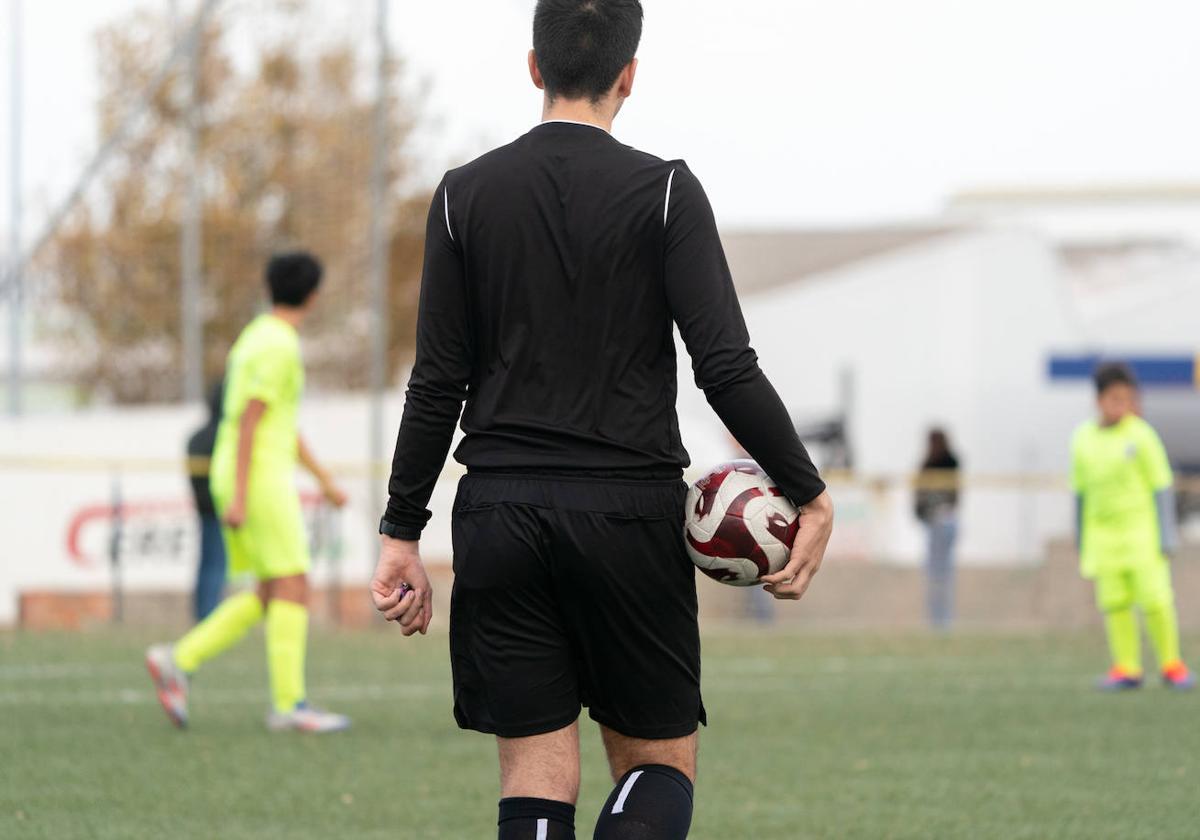 Un árbitro, durante un partido de fútbol base.