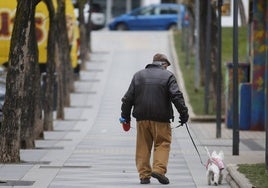 Una persona mayo paseando a su perro.