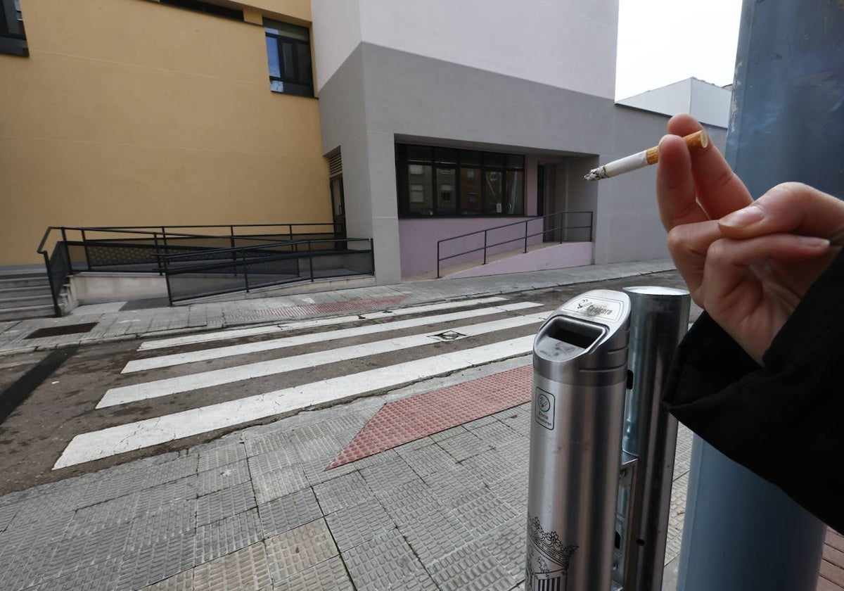 Una persona fumando en el cenicero frente a la escuela de música 'Santa Cecilia'.