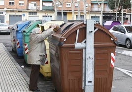 Una mujer deposita residuos orgánicos en el contenedor marrón.