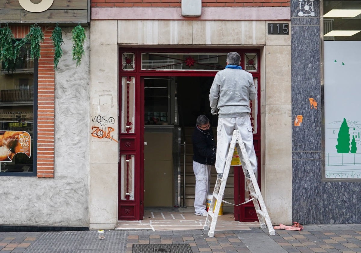 Dos profesionales pintan el portal de un edificio de Salamanca.