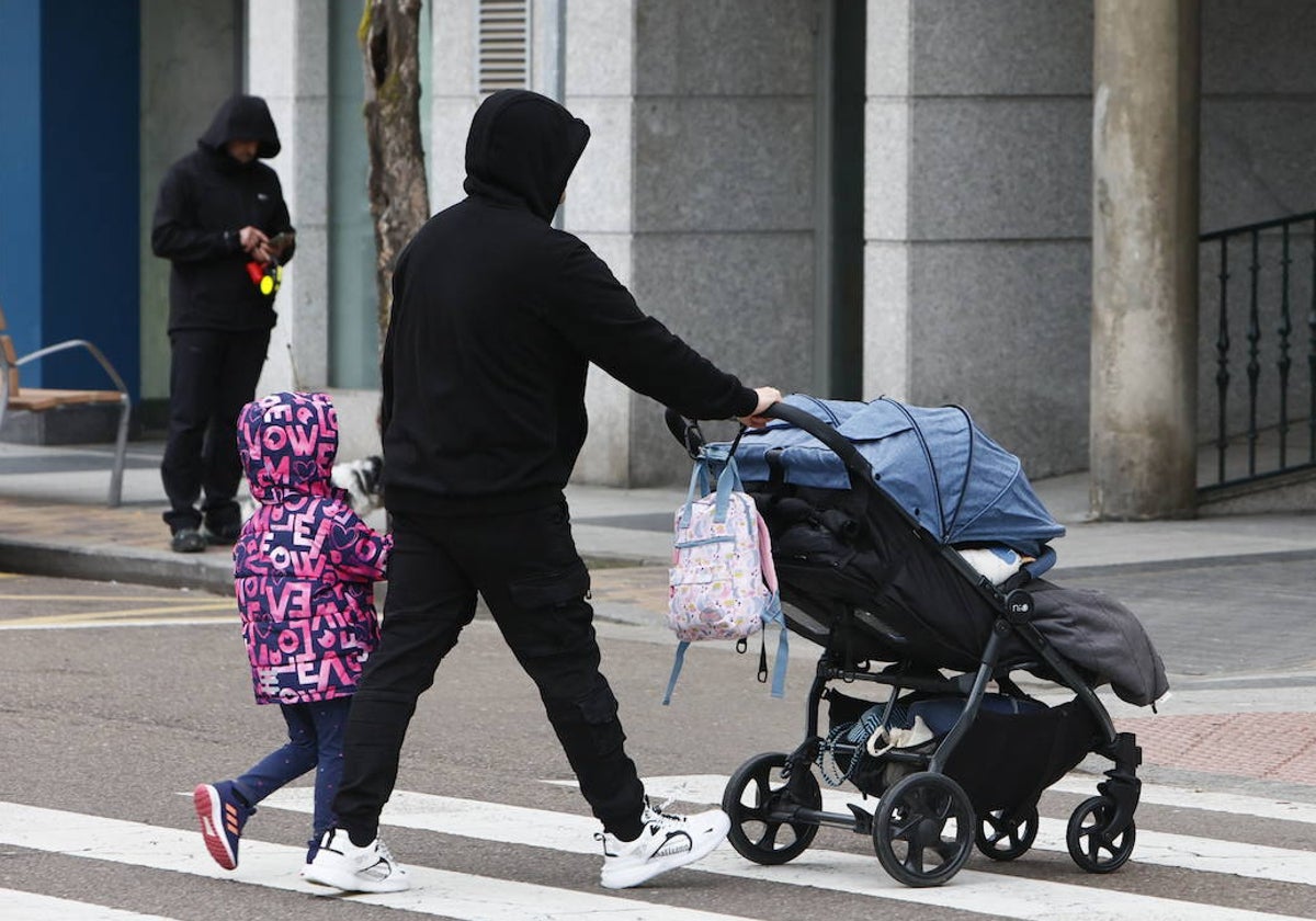 Un padre con un niño de la mano y un carrito de la otra.