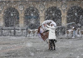 Una mujer bajo la nieve en la Plaza Mayor de Salamanca.