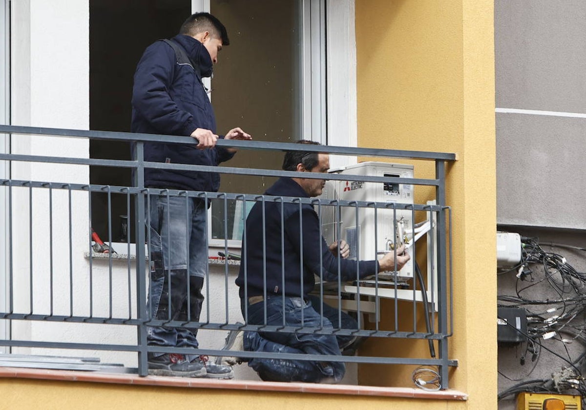 Dos trabajadores, en el balcón de una vivienda.