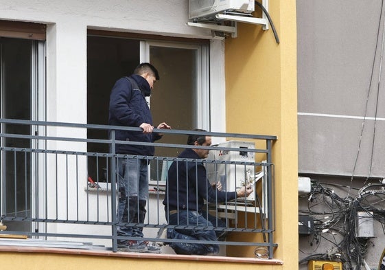 Dos trabajadores, en el balcón de una vivienda.