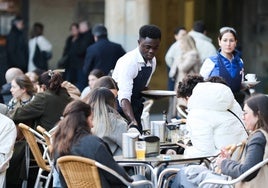 Un camarero atiende a clientes de una terraza de la Plaza Mayor.