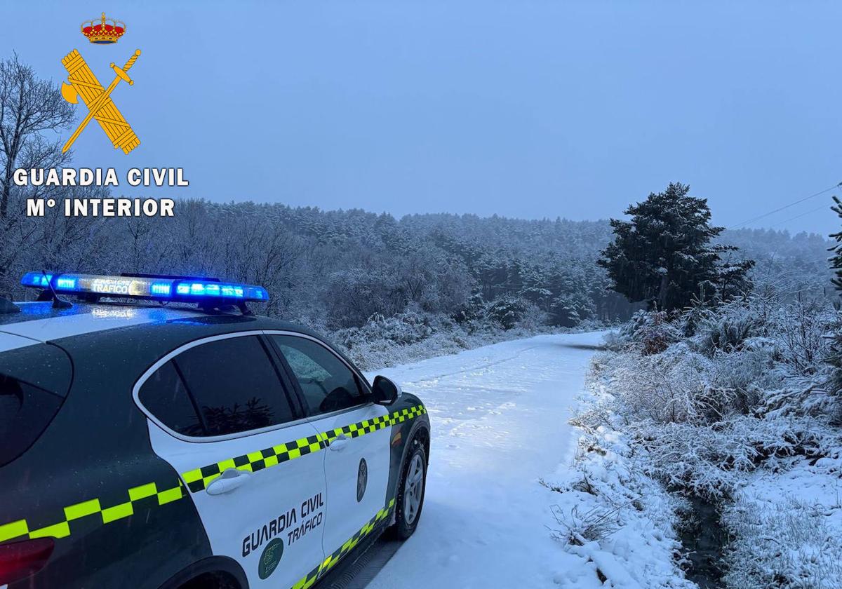 Coche de la Guardia Civil interviniendo en una carretera nevada.