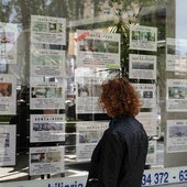 Una mujer mira anuncios de venta de pisos en una inmobiliaria.