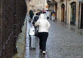 Turistas transportan sus maletas bajo la lluvia de Salamanca.