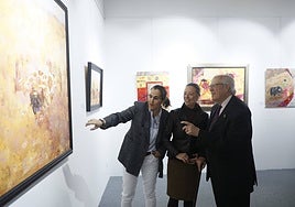 La pintora Cristina Clemares explica su obra al presidente del Casino, Pedro Méndez, y a la comisaria, María Eugenia Bueno.