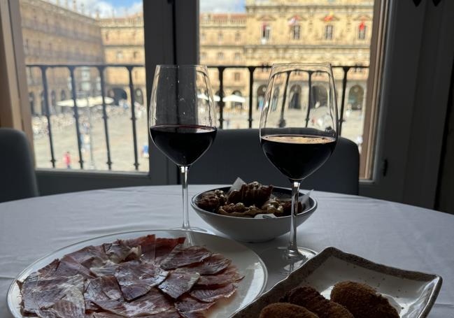 Vistas a la Plaza Mayor con un plato de jamón ibérico, croquetas y vino.