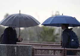 Dos personas se protegen de la lluvia con un paraguas.