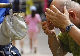 Un turista se refresca en una fuente.