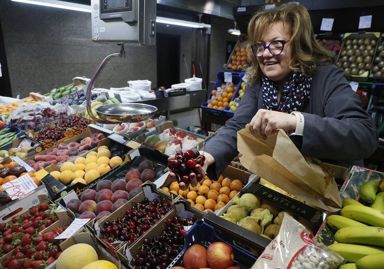 Nati Rodríguez cogiendo unas cerezas en su puesto del Mercado Central.