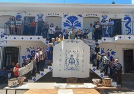 Vecinos, autoridades y los artistas posan junto al mural de la fachada del Ayuntamiento.