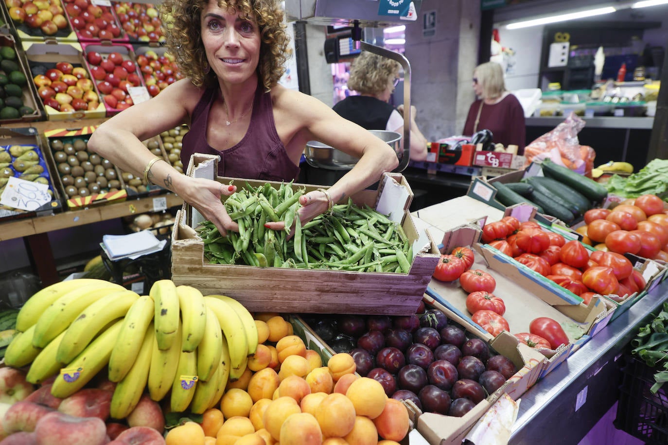 Susana, frutera del Mercado, sostiene una caja llena de guisantes.
