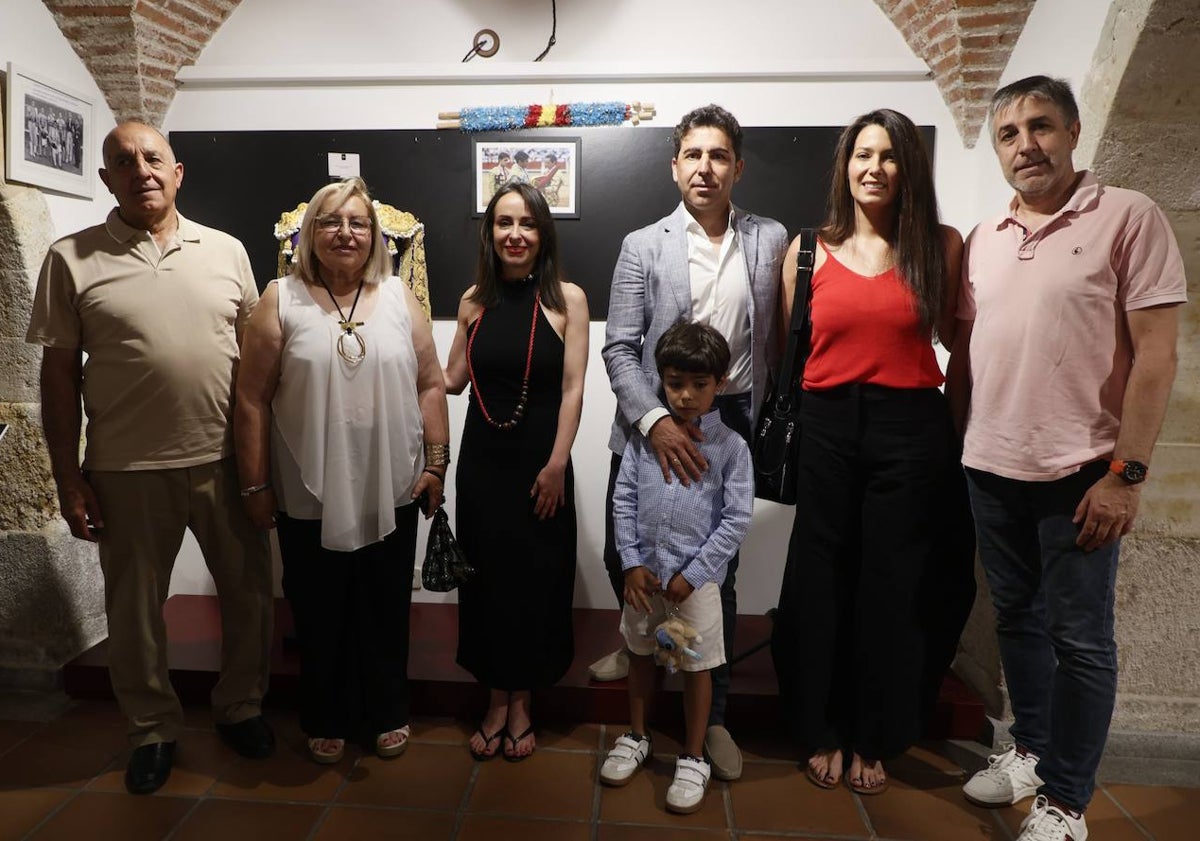 Imagen principal - Javier Valverde junto a su familia posando con el terno donado al museo taurino, que aparece en la imagen inferior. Y en otra imagen colgando un cuadro con la fotografía de su alternativa.
