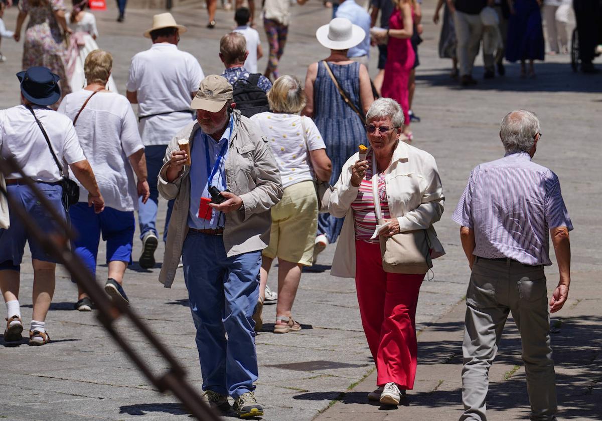 Dos turistas pasean por el centro de la ciudad comiendo un helado.