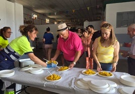 Los vecinos del municipio recogiendo su plato de paella en el centro polivalente.