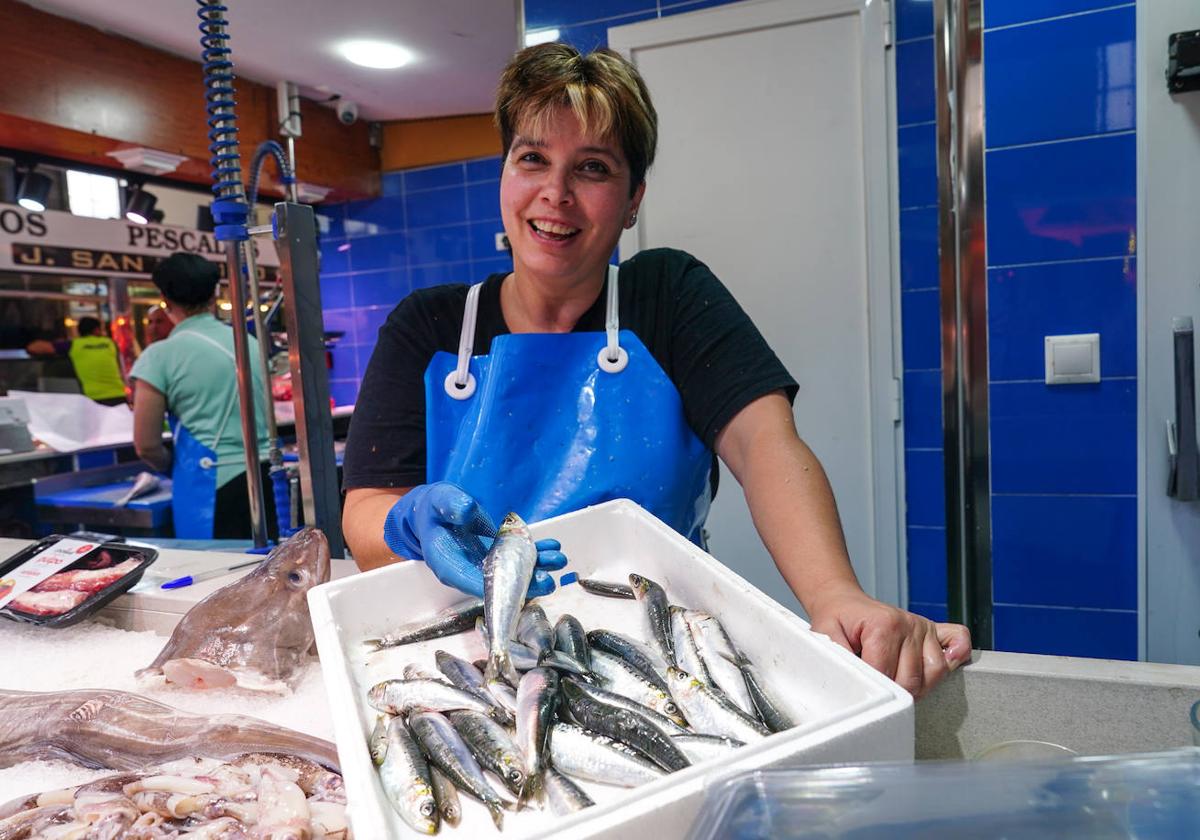 Una pescadera del puesto nº 48 sostiene una sardina en la mano.
