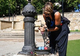 Una persona llena globos en una fuente de Salamanca.