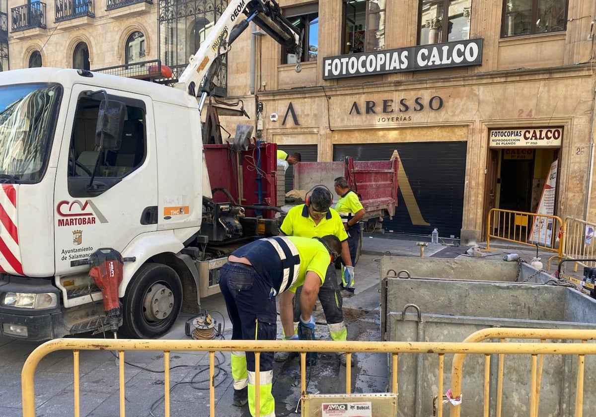 Operarios retiran las baldosas negras de pizarra para sustituirlas por otras de mayor adherencia.