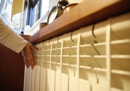 Una mujer, comprobando que el radiador está caliente.