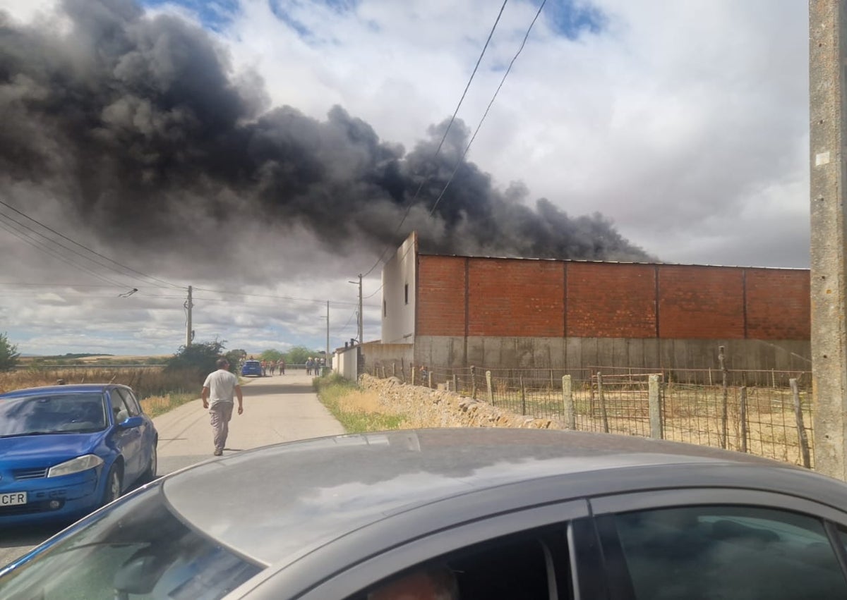 Imagen secundaria 1 - Efectivos y vecinos de la zona en el lugar del incendio de una nave en Garcihernández.