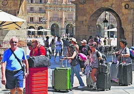 Un grupo de viajeros con grandes maletas por la plaza del Corrillo.