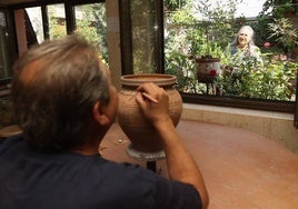 Gerardo, trabajando en una pieza en su taller mientras Reyes riega las plantas del jardín.