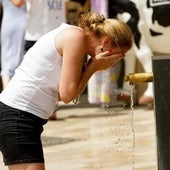 Una mujer se refresca en una fuente.