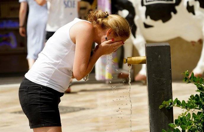 Una mujer se refresca en una fuente.