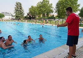 Un socorrista se dirige a los bañistas en una piscina del Helmántico llena.