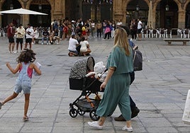 Una pareja con un carrito de bebé por la Plaza Mayor.