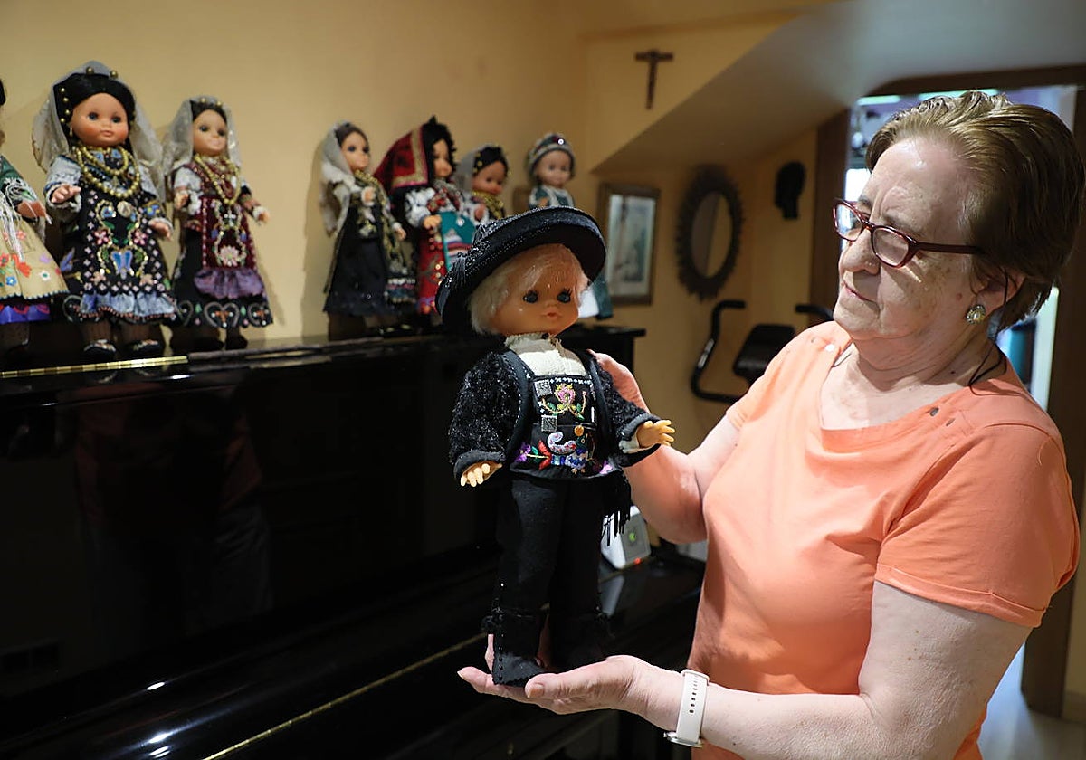Carmen Ramos sostiene el único muñeco con traje masculino que tiene en su colección.