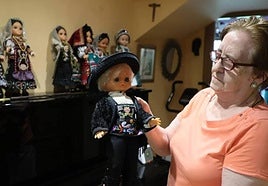 Carmen Ramos sostiene el único muñeco con traje masculino que tiene en su colección.