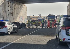 Bomberos y Guardia Civil junto al vehículo siniestrado este martes tras caer de un puente.