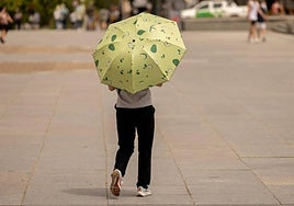 Un hombre se resguarda del sol bajo un paraguas.