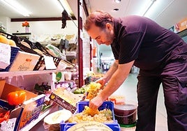 Un frutero del Mercado de San Juan cogiendo unas uvas.