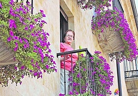 Carmen con sus flores desde el balcón de su casa.