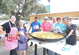 Las voluntarias y voluntarios posan junto a una de las dos paelleras