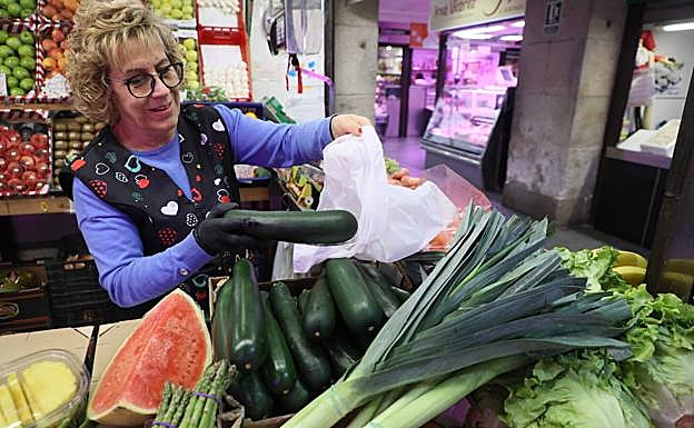 Feli, frutera del Mercado, mete un calabacín en una bolsa.