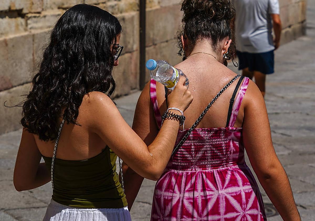 Dos chicas se refrescan con una botella de agua.