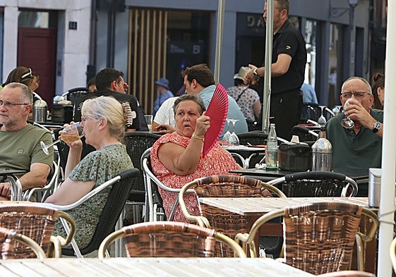 Una mujer se abanica en una terraza.
