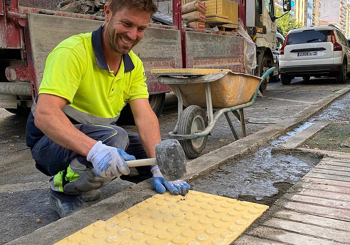Un operario coloca las baldosas podotáctiles que avisan del límite de la parada de autobús.