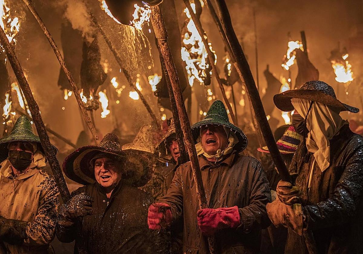 Varias personas caminan con antorchas en la celebración de la Procesión Cívica del Vítor.